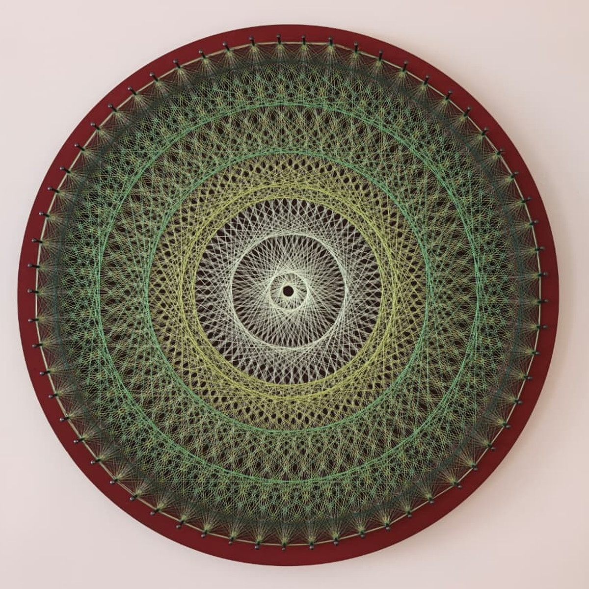 Jungle Halo, string art in shades of green on a deep burgundy frame